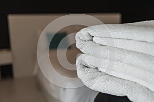 Clean white towels are folded beside bed to be ready for customers to use when it`s time to take shower because towels are