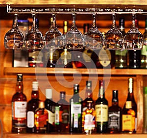 Clean wine glasses on the background of the bar with bottles of various alcoholic beverages.