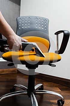Cleaner is cleaning chair with washing vacuum cleaner extractor machine for dry clean upholstered furniture. Housekeeper