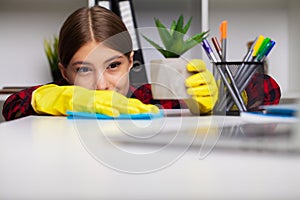 Cleaner cleans office in the yellow gloves wipes the dust off the office desk