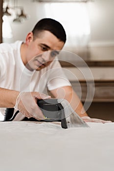 cleaner is extracting dirt from mattress using dry cleaning extractor machine. Cleaning mattress using extractor machine