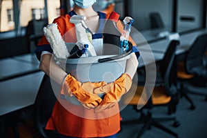 Cleaner in a face mask showing her cleaning products