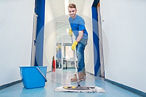 Cleaner man mopping the floor in a hall