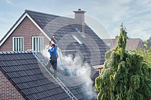 Cleaner with pressure washer at roof house cleaning roof tiles