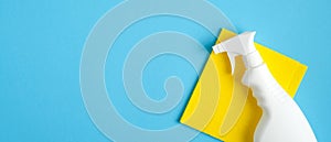 Cleaner spray bottle and yellow rag on blue background. Cleaning service banner mockup. Housecleaning and housekeeping concept.