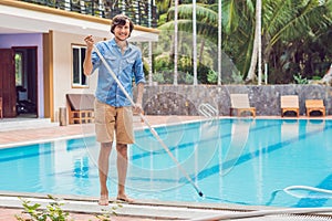 Cleaner of the swimming pool . Man in a blue shirt with cleaning equipment for swimming pools, sunny