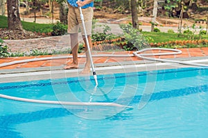 Cleaner of the swimming pool . Man in a blue shirt with cleaning equipment for swimming pools, sunny