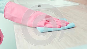 A cleaner washes the cabinet in the kitchen, wearing rubber pink gloves.