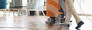 Cleaner washing floor of hotel lobby with machine closeup