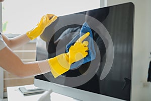 Cleaner is working, Wear rubber gloves and an apron to work, Cleaning staff wiping down office equipment, Wipe the monitor clean