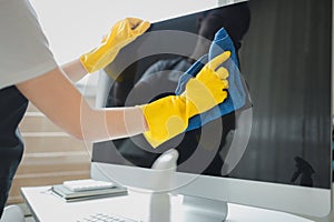 Cleaner is working, Wear rubber gloves and an apron to work, Cleaning staff wiping down office equipment, Wipe the monitor clean