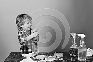 Cleaning activities concept. Kid with laughing face spraying water out of spray bottle.