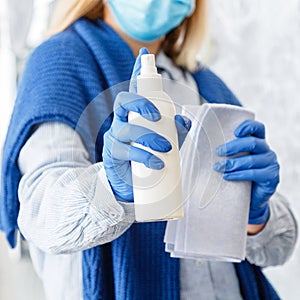Cleaning by antibacterial alcohol spray. Woman Houseworker in rubber blue gloves clean by cloth rag, sanitize spray Surfaces. New