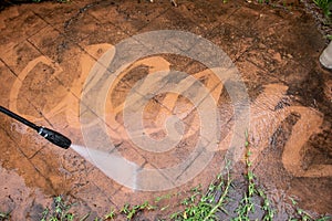 Cleaning backyard paving tiles with pressure washer