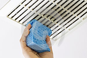 Cleaning Bathroom Fan Vent Cover with Sponge photo