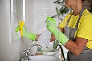 Cleaning the bathroom. The girl rubs the sink and mirror.