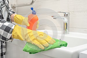 cleaning bathroom sink and faucet with detergent in bathroom. Man doing chores cleaning bathroom at home. cleaning service.