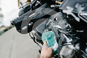 Cleaning black touristic motorbike with water