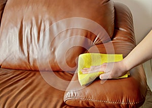 Cleaning brown sofa with a yellow cloth