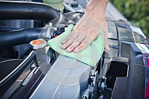 Cleaning the car engine with green microfiber cloth