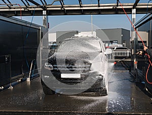 Cleaning car on self service car wash. Man spread soap using jet sprayer. Foam on the car