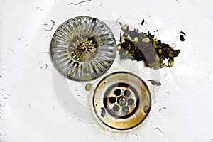 Cleaning of clogged sieves in stainless steel sink, rotten vegetables in waste, hygiene in the kitchen. Waste hole, strainer