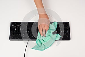 Cleaning computer keyboard in office with a wet wipe rag, dusty and dirty electronic, housework