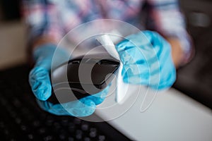 Cleaning a computer mouse device with a disposable antibacterial wipe during coronavirus pandemic emergency using hand sanitizer.