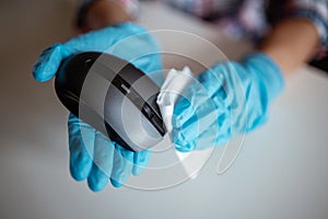Cleaning a computer mouse device with a disposable antibacterial wipe during coronavirus pandemic emergency using hand sanitizer.