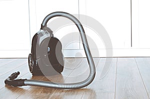 cleaning concept. Black vacuum cleaner stands on the floor in the apartment