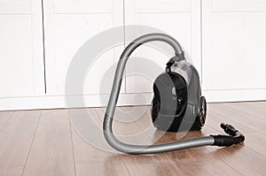cleaning concept. Black vacuum cleaner stands on the floor in the apartment