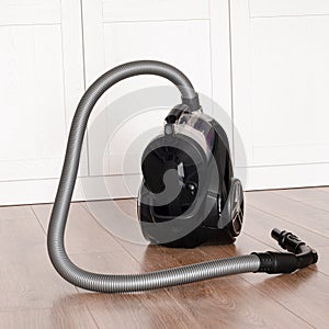 cleaning concept. Black vacuum cleaner stands on the floor in the apartment