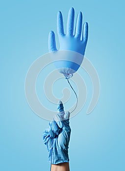 Cleaning concept. Concept of medicine. A hand in a blue glove holds an inflatable ball in the shape of a glove on a blue