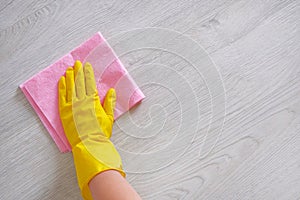 Cleaning concept in office, home. Female hand with pink rag is wipes light wooden floor at home. Housework and housekeeping