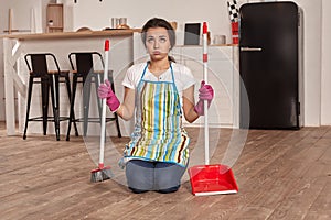 Young woman sweeping floor on the kitchen