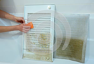 Cleaning a cooker hood filter from fat. A close-up of cleaning a greasy kitchen hood, range hood filters, grates with a sponge