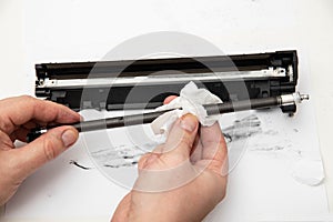 Cleaning the details of the laser cartridge printer from the remnants of the old toner on a white background. Refilling the Toner