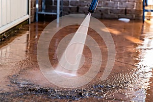 Cleaning dirty backyard paving tiles with pressure washer cleaner