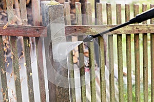 Cleaning dirty garden fence post with high pressure washer