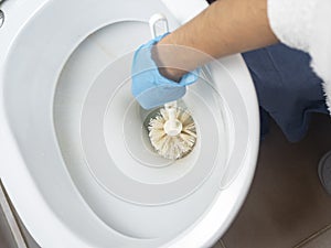Cleaning a dirty home toilet with a brush and cleaning products. hand protection with gloves
