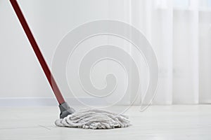 Cleaning dirty parquet floor with mop indoors. Space for text