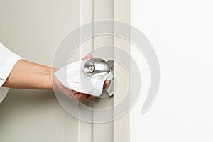 Cleaning door knob with alcohol spray for Covid-19 Coronavirus prevention