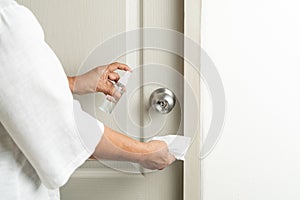 Cleaning door knob with alcohol spray for Covid-19 Coronavirus prevention