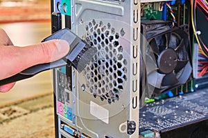 Cleaning dust from a cooler inside a computer case, using a small vacuum tube with a brush. PC maintenance concept