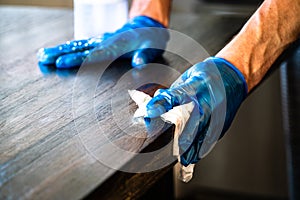 Cleaning the edge of the table with protective gloves during Covid-19 pandemic