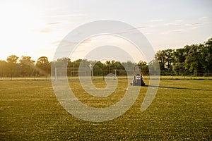 Cleaning football lawn. A man mowing the grass at the football stadium. Man on a tractor