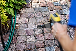 Cleaning the garden cobblestone pathway with a high pressure washer