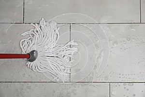 Cleaning grey tiled floor with string mop, top view. Space for text