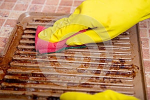 Cleaning the grill. Hands in yellow gloves clean the dirty grill of grease and burns with a cleaning agent. electric grill hygiene