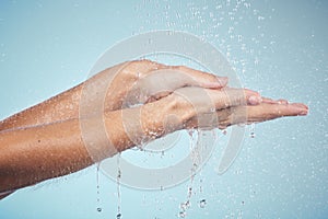 Cleaning, hands and water splash on woman in studio, blue background and healthcare mockup and washing for skincare